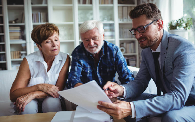 Senior couple planning their investments with financial adviser in living room