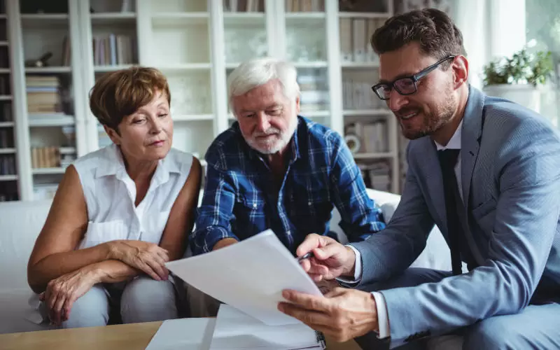 Senior couple planning their investments with financial adviser in living room